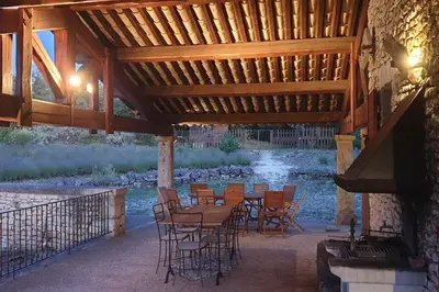 a patio with a table and chairs under a wooden roof at Maison de caractère dans Luberon avec piscine in Saignon