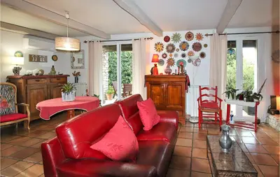 a living room with a red leather couch and a table at Lovely Home In Cheval-Blanc in Cheval-Blanc