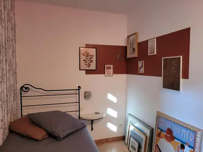 a bedroom with a bed and a table and pictures on the wall at Appartement climatisé sur golf de L'Isle-Sur-La-Sorgue in Saumane-de-Vaucluse