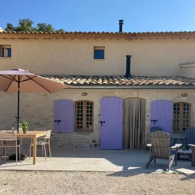 a building with purple doors and a table with an umbrella at La Grisonne - Gîte Nordine in Revest-du-Bion