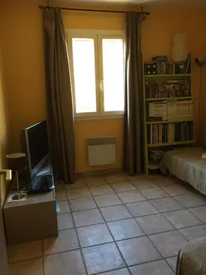 a bedroom with a bed and a tv and a window at House quiet and wooded in Aix-en-Provence