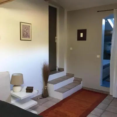 a living room with stairs and a table and a lamp at House quiet and wooded in Aix-en-Provence