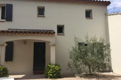 a white house with a black door and a tree at House quiet and wooded in Aix-en-Provence