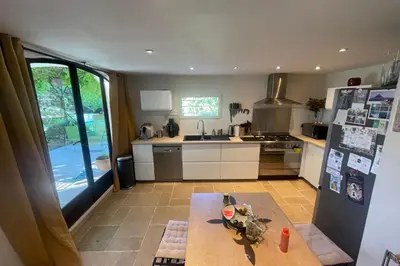 a kitchen with a table and a refrigerator at House quiet and wooded in Aix-en-Provence