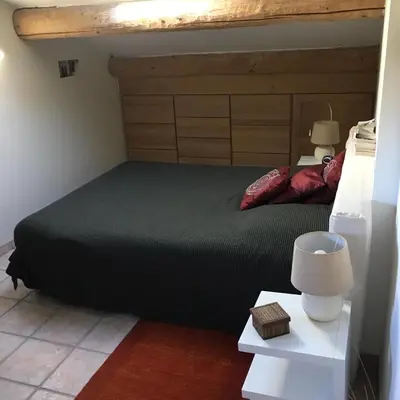 a bedroom with a black bed with a wooden headboard at House quiet and wooded in Aix-en-Provence