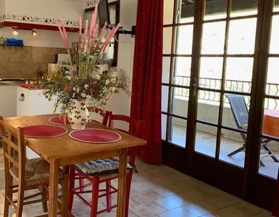 a kitchen with a table with chairs and a vase with flowers at Gîte La loge 142 route de CARPENTRAS 84210 VENASQUE in Venasque