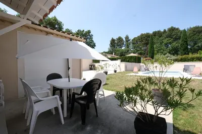 a patio with a table and chairs and an umbrella at very pleasant villa with private swimming pool, in a residential area near the center of saint-rémy-de-provence - 8 people in Saint-Rémy-de-Provence