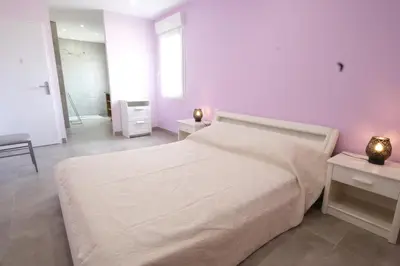 a white bedroom with a large bed and two tables at very pleasant villa with private swimming pool, in a residential area near the center of saint-rémy-de-provence - 8 people in Saint-Rémy-de-Provence