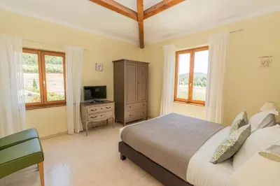 a bedroom with a bed and a tv and windows at Mon Ventoux - Cozyhotes in Sault-de-Vaucluse