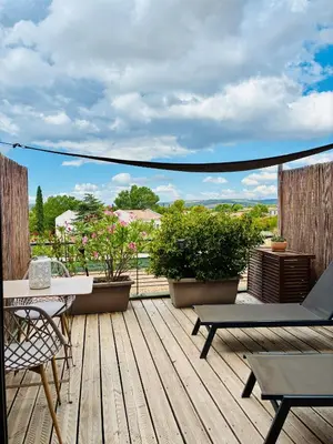 a wooden deck with chairs and tables on a balcony at Studio Nuitée en Provence 2 in Aix-en-Provence