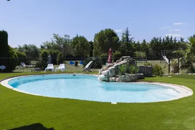 a swimming pool in a yard with a rock wall at Roulotte chez Manon en Luberon in Lagnes