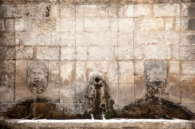 a stone wall with two statues in a fountain at Gîte St Roch en Luberon in Castellet