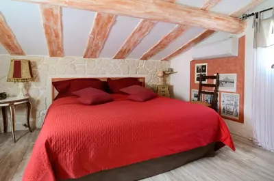 a red bed with red pillows in a bedroom at Gîte la Saume in Lambesc