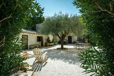 a garden with two chairs and a tree at Mas Sylvie - Isle-sur-la-Sorgue in LʼIsle-sur-la-Sorgue