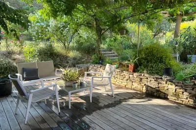 a patio with two chairs and a table and a stone wall at Beautiful house in the heart of its pine forest - private pool in Les Taillades