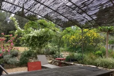 a garden with a pergola and a table and chairs at Beautiful house in the heart of its pine forest - private pool in Les Taillades