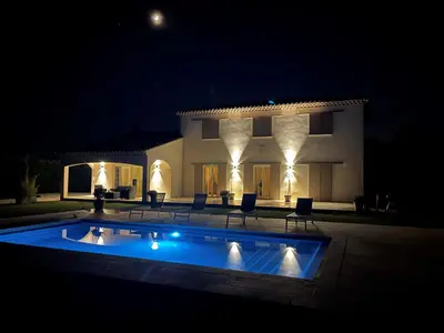 a swimming pool in front of a house at night at La Bastide Cezanne Natural elegance in Aix-en-Provence