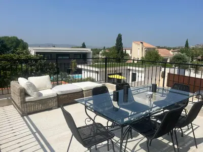 a patio with a table and chairs and a couch at Haut de villa avec piscine privée et extérieur in Lançon-Provence
