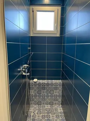 a blue tiled bathroom with a shower and a window at Haut de villa avec piscine privée et extérieur in Lançon-Provence
