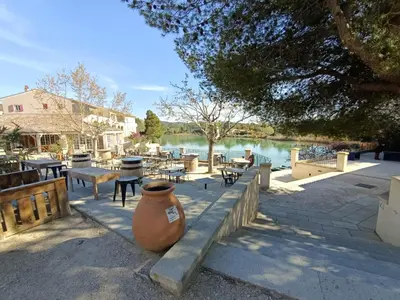 a large vase sitting on a sidewalk next to a lake at Appartement vue panoramique au domaine et golf de pont royal in Mallemort
