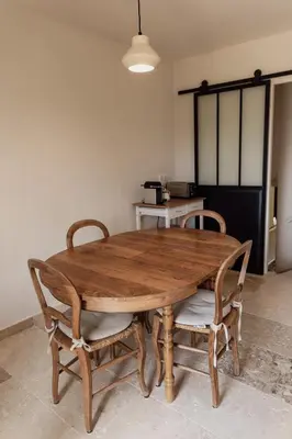 a wooden table with two chairs and a kitchen at L'Olivier in Mormoiron