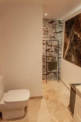a bathroom with a toilet and a brick wall at L'Olivier in Mormoiron