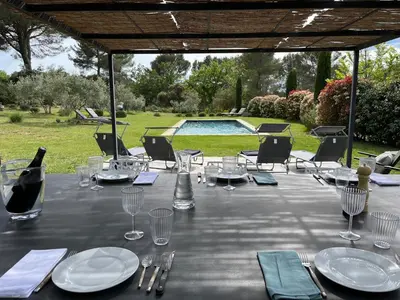 a table with glasses and plates and a bottle of wine at Lou Pantai, House, 5 bedrooms, 8 people, AC, Pool, Large garden,4km from AIX EN PROVENCE in Aix-en-Provence