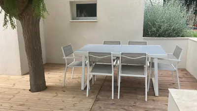 a white table and chairs on a patio with a tree at La Manuia in Ventabren