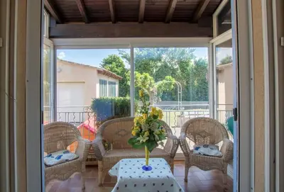 a porch with a table with a vase of flowers on it at La Villa des Sorgues in LʼIsle-sur-la-Sorgue