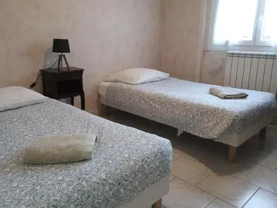a bedroom with two beds and a table with a lamp at La Villa des Sorgues in LʼIsle-sur-la-Sorgue