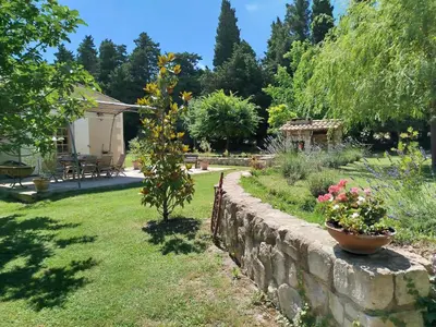 a garden with a stone retaining wall and flowers at Charmante bergerie dans un cadre bucolique in Saint-Rémy-de-Provence