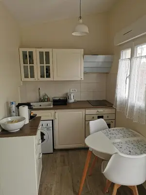 a kitchen with white cabinets and a table and chairs at Studio indépendant à 2 minutes du golf du Luberon in Pierrevert