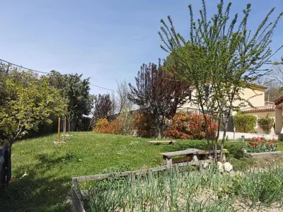 a garden with a wooden bench in the grass at Studio indépendant à 2 minutes du golf du Luberon in Pierrevert