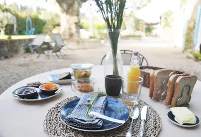 a table with plates of food and a vase at Le Mas des Perrines Maison d’Hôtes in Pernes-les-Fontaines