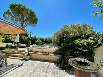 a garden with a pool and a table and a umbrella at Le Mas des Perrines Maison d’Hôtes in Pernes-les-Fontaines