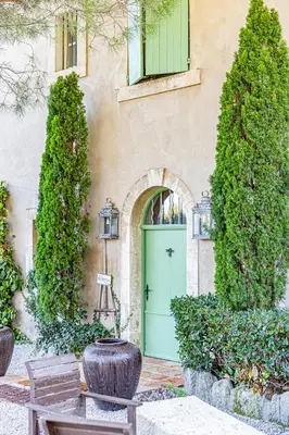 a green door of a building with trees and a bench at Maison Bournissac in Noves