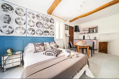 a bedroom with a large bed with faces on the wall at Le Bonheur -studio terrasse centre-ville - in LʼIsle-sur-la-Sorgue