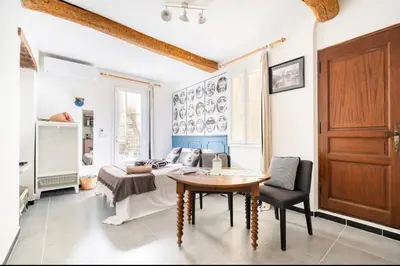 a living room with a table and a couch at Le Bonheur -studio terrasse centre-ville - in LʼIsle-sur-la-Sorgue