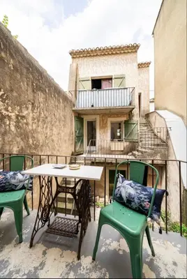 a table and chairs on a balcony with a building at Le Bonheur -studio terrasse centre-ville - in LʼIsle-sur-la-Sorgue