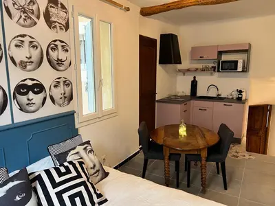 a room with a bed and a table and a kitchen at Le Bonheur -studio terrasse centre-ville - in LʼIsle-sur-la-Sorgue