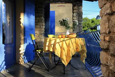 a table with a yellow table cloth on a balcony at La Cerisaie, maison spacieuse en Lubéron in Saint-Martin-de-Castillon