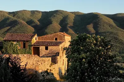 an old stone building with mountains in the background at La Cerisaie, maison spacieuse en Lubéron in Saint-Martin-de-Castillon