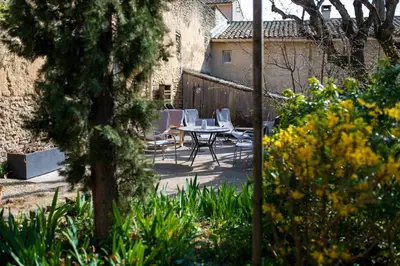 a patio with a table and chairs in a garden at Gites Provence et Nature - Ambiance familiale et conviviale en Luberon in Cabrières-dʼAvignon