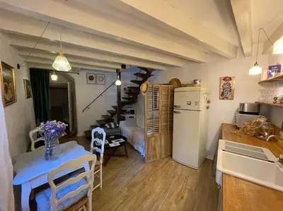 a kitchen and living room with a table and a refrigerator at Duplex Atelier / coeur de Lourmarin in Lourmarin