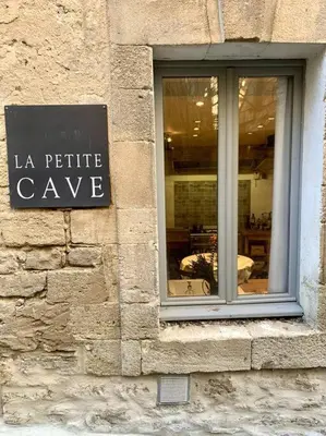 a sign on the side of a stone building at La Petite Cave in Saignon