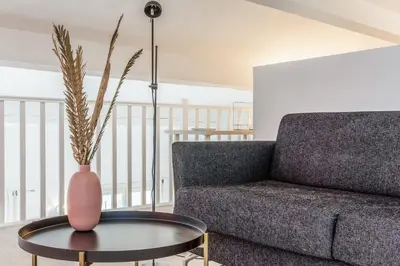 a living room with a couch and a vase on a table at Appartement Cezanne - Welkeys in Aix-en-Provence