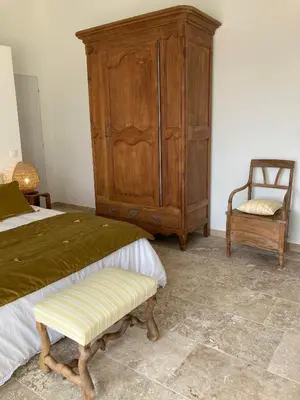 a bedroom with a large wooden cabinet and a chair at Chambre d'hôtes de la cime in Cabrières-dʼAigues
