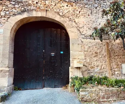 a large black door in a stone building at Maison de caractère au coeur de la Provence in Robion en Luberon