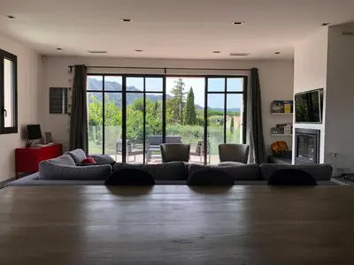 a living room with a couch and a large window at Maison contemporaine dans le village d'Eygalières in Eygalières