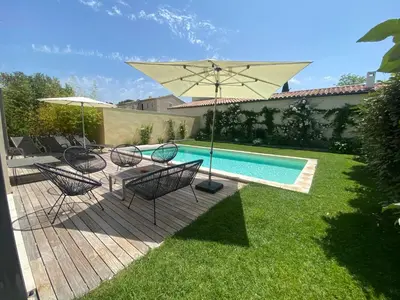a patio with chairs and an umbrella next to a pool at Maison contemporaine dans le village d'Eygalières in Eygalières